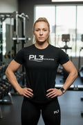 Woman wearing black PL3 Athletics performance training shirt in gym